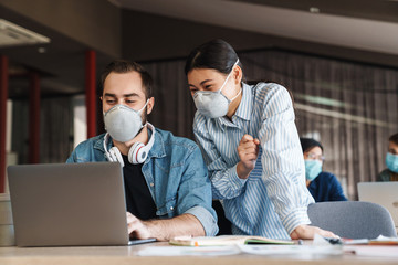 Poster - Photo of joyful students in medical masks studying with laptop