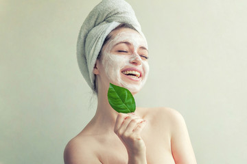 Woman face with green leaf and cream or nourishing mask