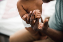 Afro American Man Holding Hand Of Newborn Child