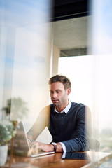 Wall Mural - Young businessman working at a table at home