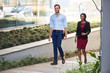 © marvent - Smiling young businesspeople walking together outside of their office building