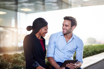 Wall Mural - Laughing young businesspeople sitting outside of their office building