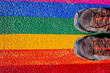 © Road Red Runner - A man steps on his boots with the gay flag, painted on the ground, a concept of contempt for rights.