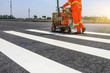 Road workers use hot-melt scribing machines to painting pedestrian crosswalk on asphalt road surface in the city.