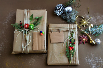 Merry Christmas or Happy New Year concept with two gifts box wrapped  by kraft paper on brown paper surface with pine cones