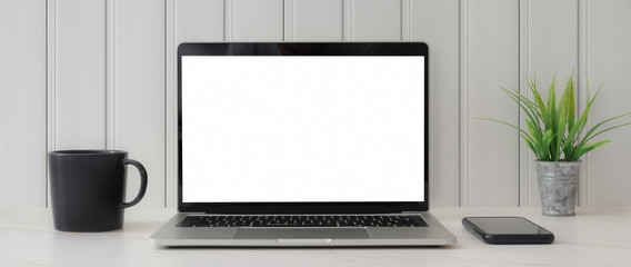 Canvas Print - cropped shot of workspace with blank screen laptop, smartphone, coffee cup and tree pot on white tab