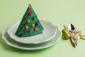 Wall Mural - Green color paper napkin folded in pine tree shape,stand in plate near cutlery set.Christmas or New Year design.