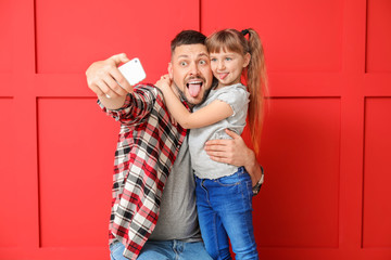 Poster - Father and his little daughter taking selfie on color background