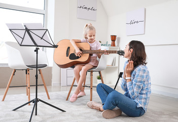 Wall Mural - Private music teacher giving guitar lessons to little girl at home