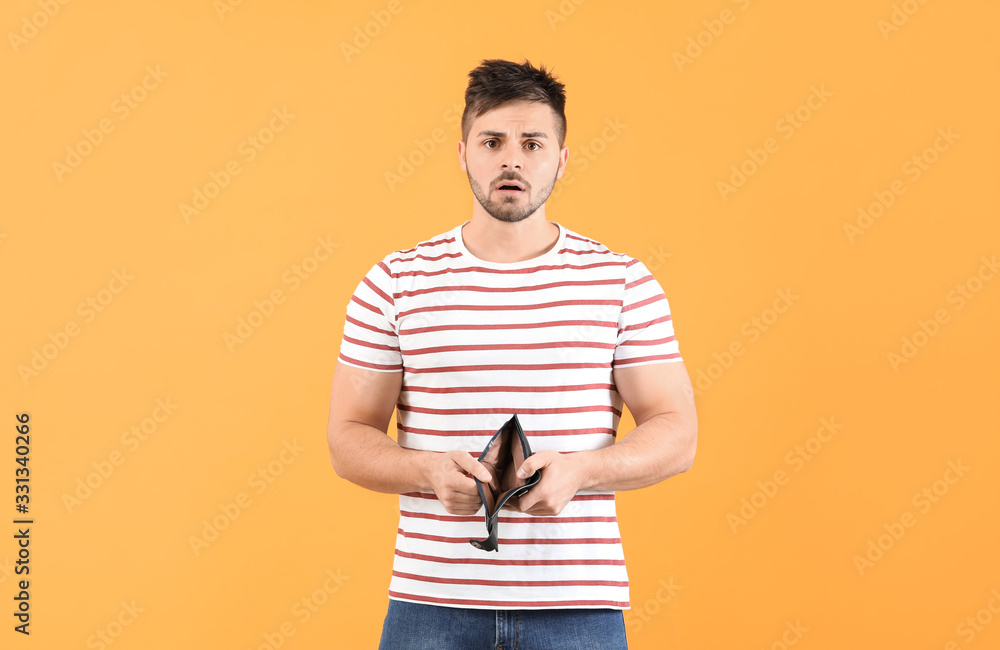 Sad man with empty purse on color background