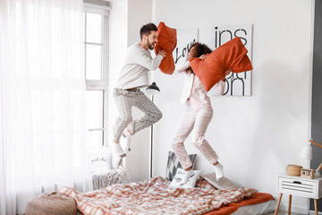 Sticker - Happy young couple fighting on pillows in bedroom