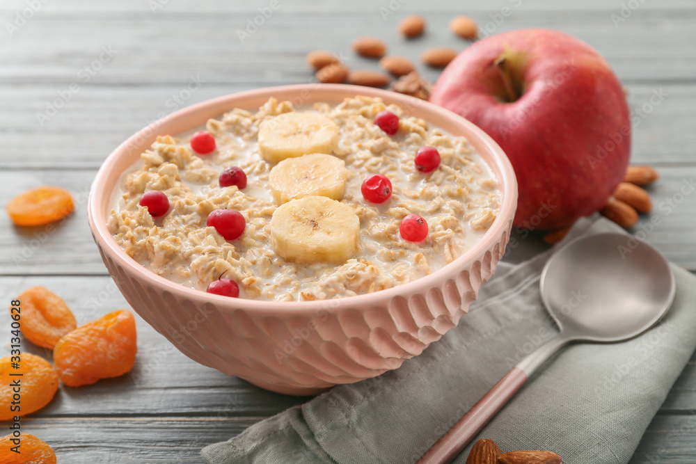 Bowl with tasty sweet oatmeal on table - obrazy, fototapety, plakaty 