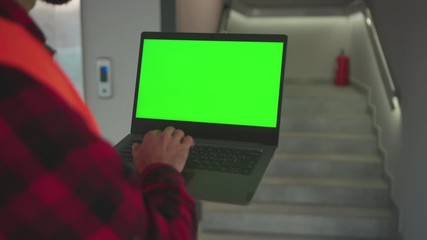 Wall Mural - Close up young hands engineer using laptop computer with green screen inside building background stairs worker project occupation builder technology mock-up professional male computer slow motion