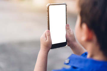 Cute little boy child using technology of smartphone outdoors.Kid felling relaxing and enjoy time play phone with white mockup blank screens.Communication and technology concept