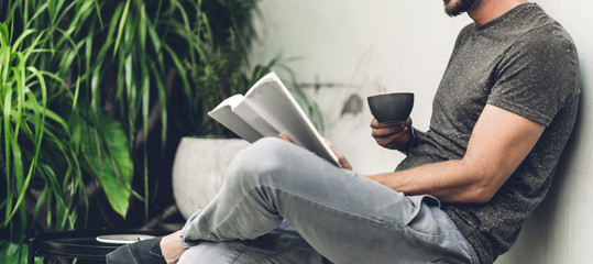 Handsome hipster man relaxing read the paper book work study and looking at page magazine while sitting on chair in cafe and restaurant