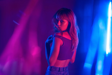 Wall Mural - Sexy sensual fashion attractive young 20s girl model beautiful blond hair at purple studio background. Hot trendy stylish woman beauty face look at camera stand in neon violet light concept. Portrait.