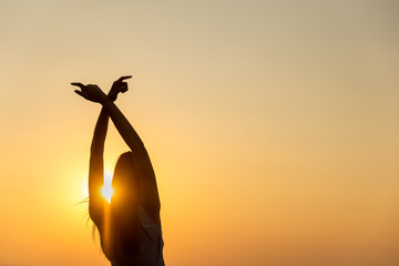 Wall Mural - Young woman relaxing in summer sunset sky outdoor,breathing fresh air raising arms.