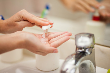 Wall Mural - Woman antibacterial liquid soap for hands in bathroom. People and healthcare concept.