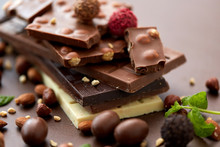 Sweets, Confectionery And Food Concept - Close Up Of Different Chocolate Bars, Candies And Nuts On Brown Background