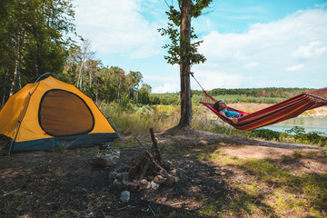 Wall Mural - woman laying on hammock at camp near lake summer hiking concept