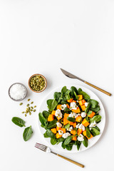 Wall Mural - Healthy food concept. Salad with pumpkin and basil on white background top-down copy space