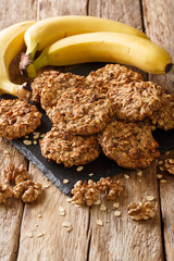 Wall Mural - Tasty banana cookies with oatmeal and walnuts close-up on a slate board. vertical