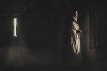 Catholic Nun Prays In The Dark Old Church. Historical Cosplay Of Vintage Church. A Woman In Old Nun Catholic Cassock