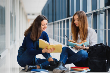 Wall Mural - Female students sitting on the floor and reading notes before exam