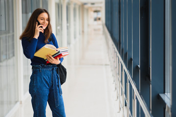 Wall Mural - Portrait of a pretty female student with books and a backpack in the university hallway