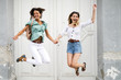 Two happy joyful young women jumping and laughing together