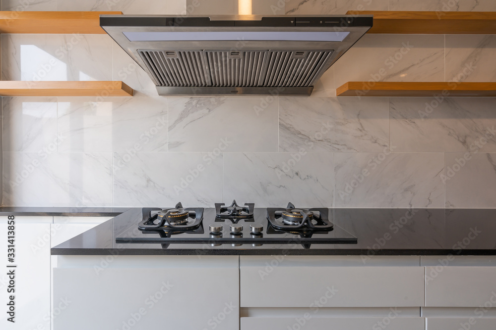 New kitchen gas stove on the black countertop and fume extractor ...