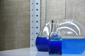 three laboratory flasks with blue liquid on the rack