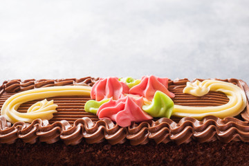 Wall Mural - Chocolate rectangular cake decorated with cream roses on a light table. Sweet food is a confectionery business. copy space Selective focus