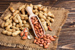 Peanuts in a shell and cleaned in a wooden scoop on a sackcloth on a wooden background. Copy space, close up