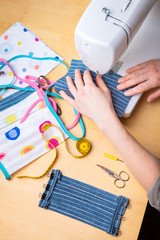 Wall Mural - Woman hands using the sewing machine to sew the face mask during the coronavirus pandemia. Domestic sewing due to the shortage of medical materials.