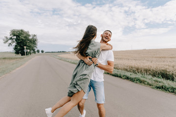 Wall Mural - Romantic young couple sharing a special moment while on a road trip.Man driving car with girlfriend.Sexy girl laying on car and kissing her boyfriend,cool outfit,having fun,sunny,man woman together