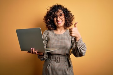 Sticker - Beautiful arab businesswoman wearing glasses working using laptop over yellow background happy with big smile doing ok sign, thumb up with fingers, excellent sign