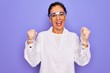 © Krakenimages.com - Middle age senior scientist woman wearing coat and laboratory glasses over purple background celebrating surprised and amazed for success with arms raised and open eyes. Winner concept.