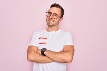 Handsome man with blue eyes wearing sticker with hello my name is message identification happy face smiling with crossed arms looking at the camera. Positive person.