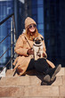 © standret - Woman in warm clothes have a walk with her little pug dog near business building that on background
