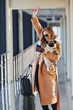 © standret - Young female passenger in warm clothes walking with her dog in airport hall