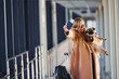 © standret - Young female passenger in warm clothes walking with her dog in airport hall