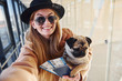 © standret - Young female passenger in warm clothes holding tickets and cute dog in hands in airport hall