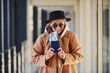 © standret - Young female passenger in warm clothes showing tickets in airport hall