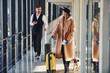 © standret - Female passenger in warm clothes, with dog and with baggage walk with man in formal wear