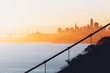 Goldener Sonnenaufgang mit Streben der Golden Gate Bridge im Vordergrund sowie Skyline von San Francisco im Hintergrund 