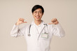 © Drobot Dean - Image of asian young male doctor smiling and pointing fingers at himself
