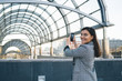© BullRun - Cheerful caucasian woman traveler using mobile phone app for shooting video ofor journey blog during vacations,smiling hipster girl look at camera taking picture on city architecture on smartphone