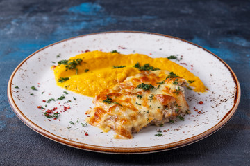 Wall Mural - Delicious baked chicken under cheese with carrot puree on a plate.