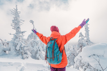 Happy single girl actively spends her free time in the mountains and snow-covered forest. The concept of achievement goals and sport as a hobby